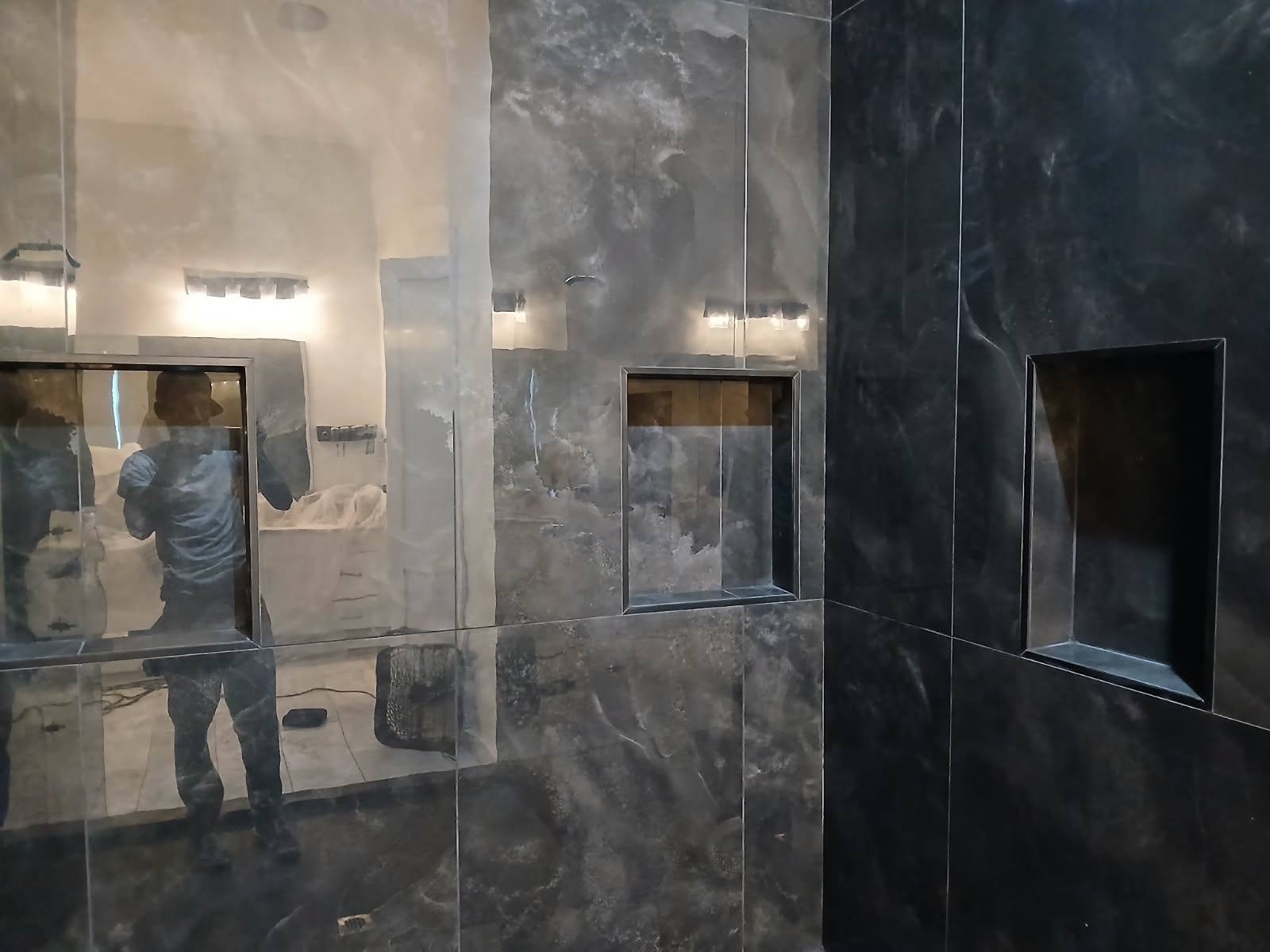 Black marble shower walls with built-in niches during install